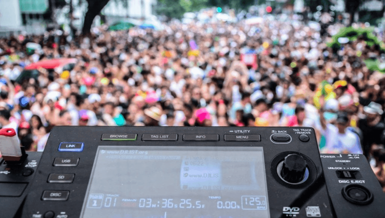 Multidão dançando em bloco de carnaval eletrônico Unidos do BPM , SP, com trio elétrico e DJ no comando