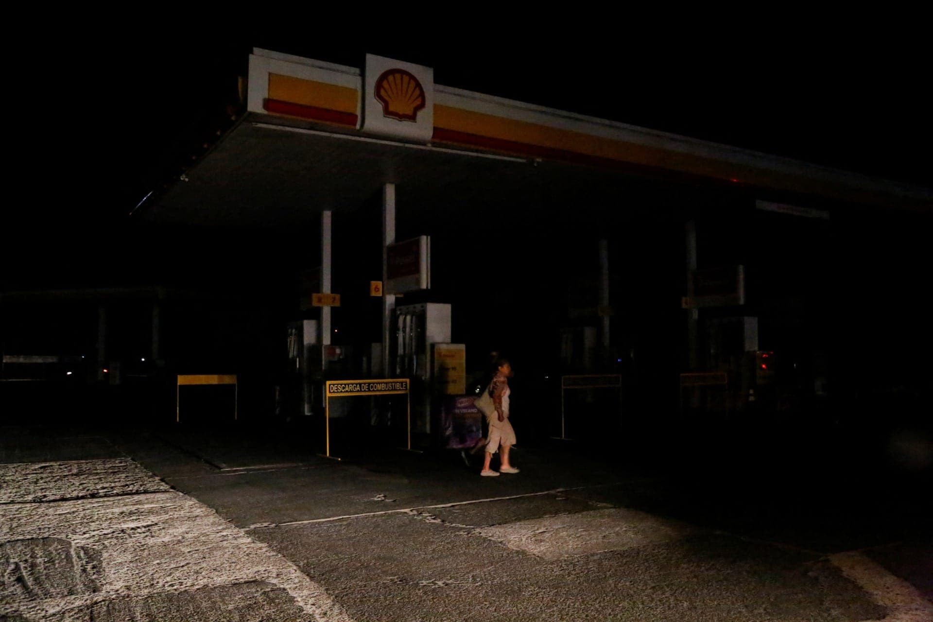 Uma mulher caminha em um posto de gasolina durante apagão em Arica, no Chile, nesta terça-feira (25)