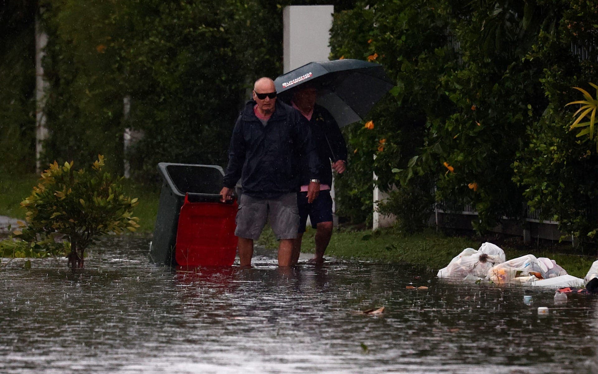 Pessoas atravessam uma rua alagada após a tempestade Alfred, em Cabarita Beach, na Austrália