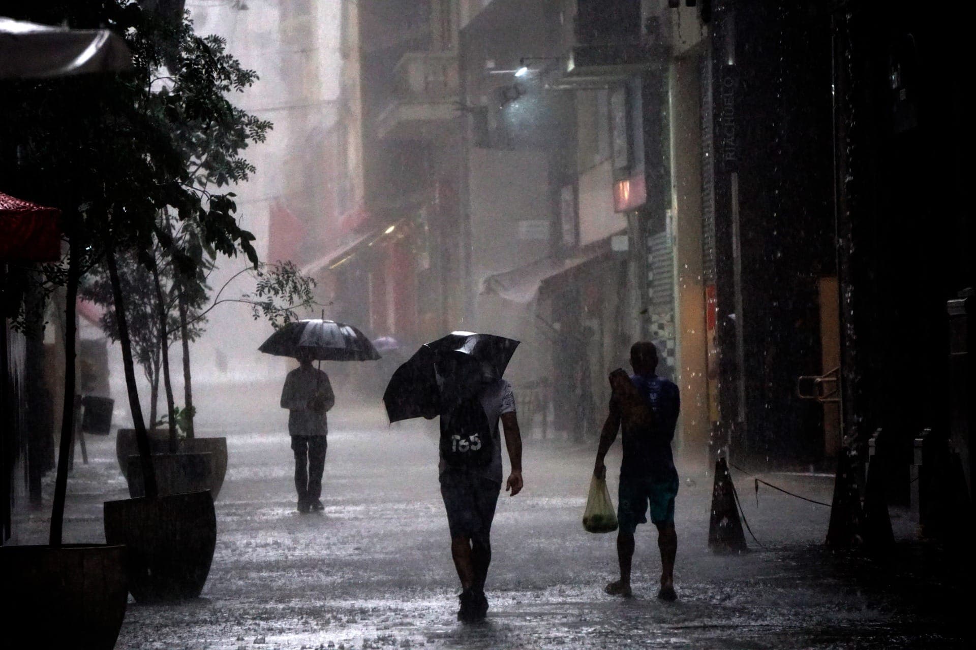 Pedestres se protegem da chuva na região central da cidade de São Paulo