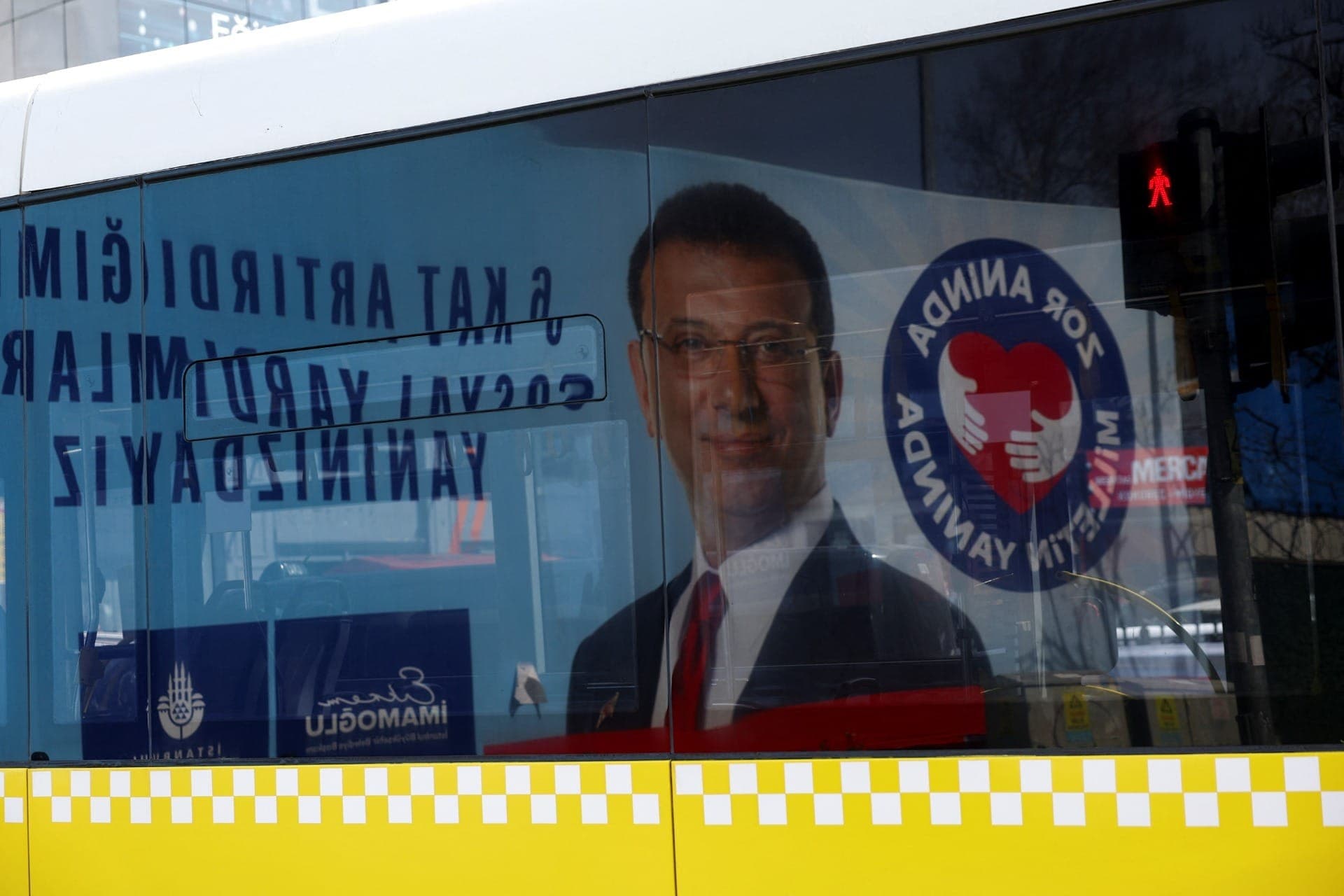 Janela de ônibus reflete foto de Ekrem Imamoglu, prefeito de Istambul