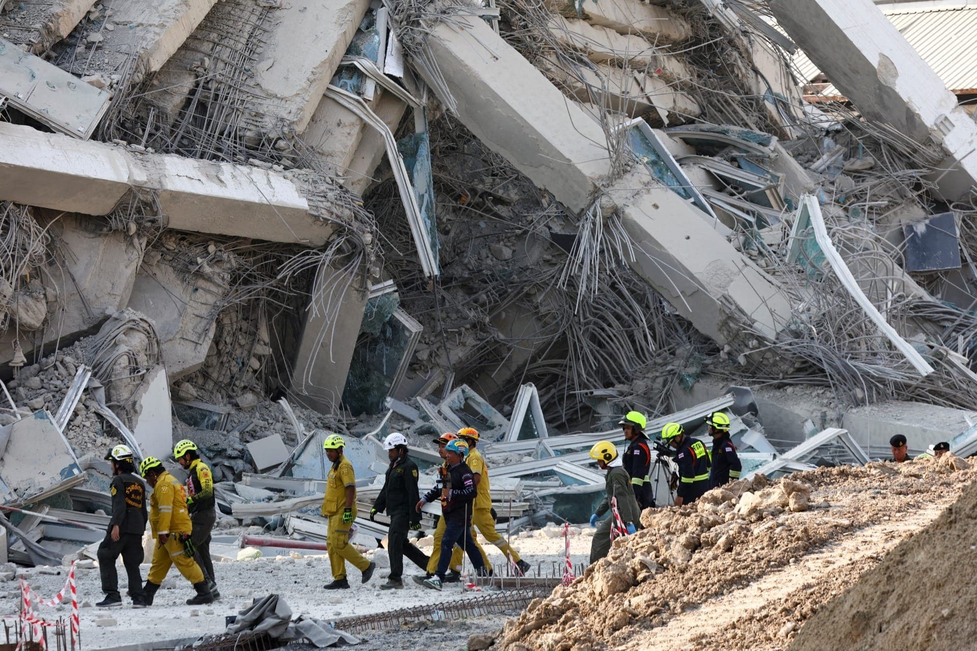 Equipes de resgate caminham perto de um prédio que desabou após um forte terremoto atingir o centro de Mianmar nesta sexta-feira, segundo serviços de monitoramento sísmico