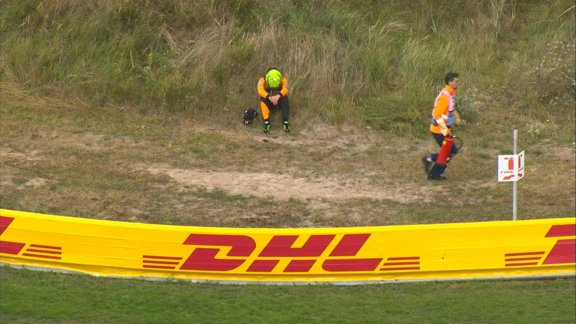 Lando Norris sentado na grama após abandonar o GP da Holanda de Fórmula 1