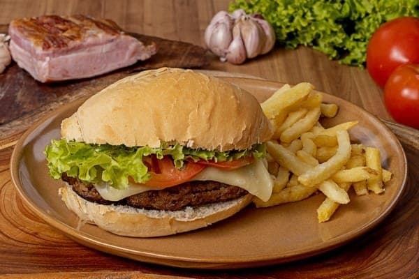 Bolinho de carne bovina, bacon, queijo muçarela derretido, alface, tomate, maionese de alho artesanal, servido no pão francês. Acompanha batatas fritas.