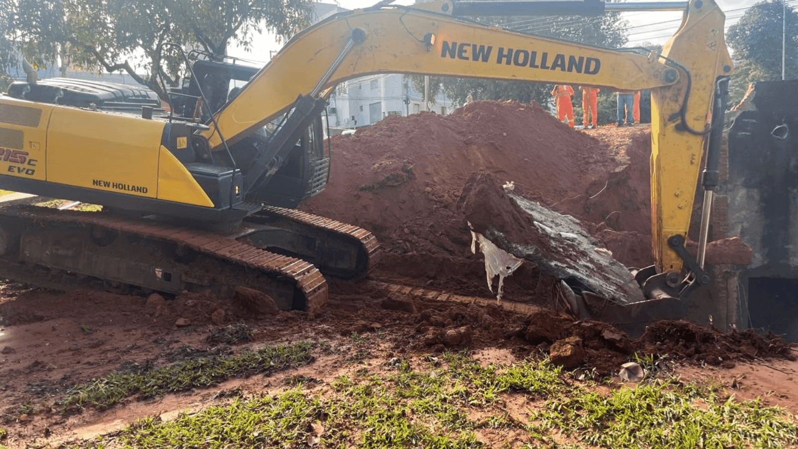 Uma retroescavadeira está no local realizando a limpeza da área