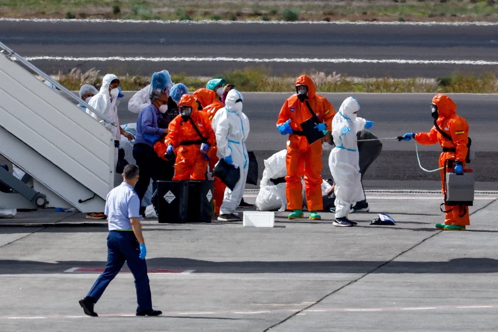 Pessoas usando equipamentos de proteção individual fazem preparativos na pista do aeroporto Tenerife Sul após a chegada do cruzeiro MV Hondius