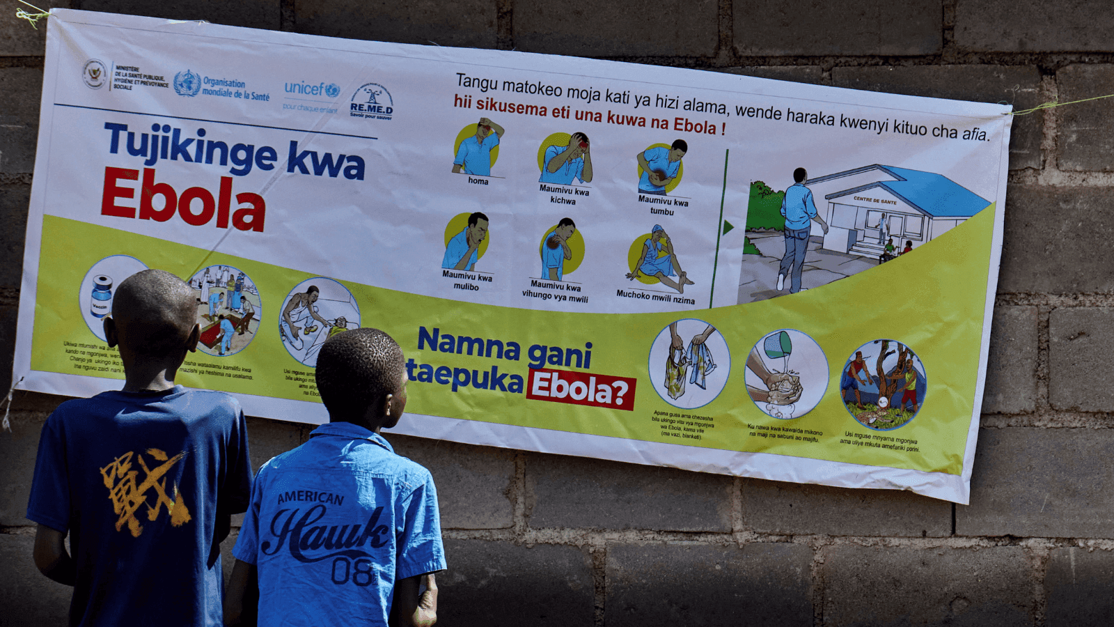 Crianças leem cartaz sobre sintomas e como evitar Ebola no RD do Congo