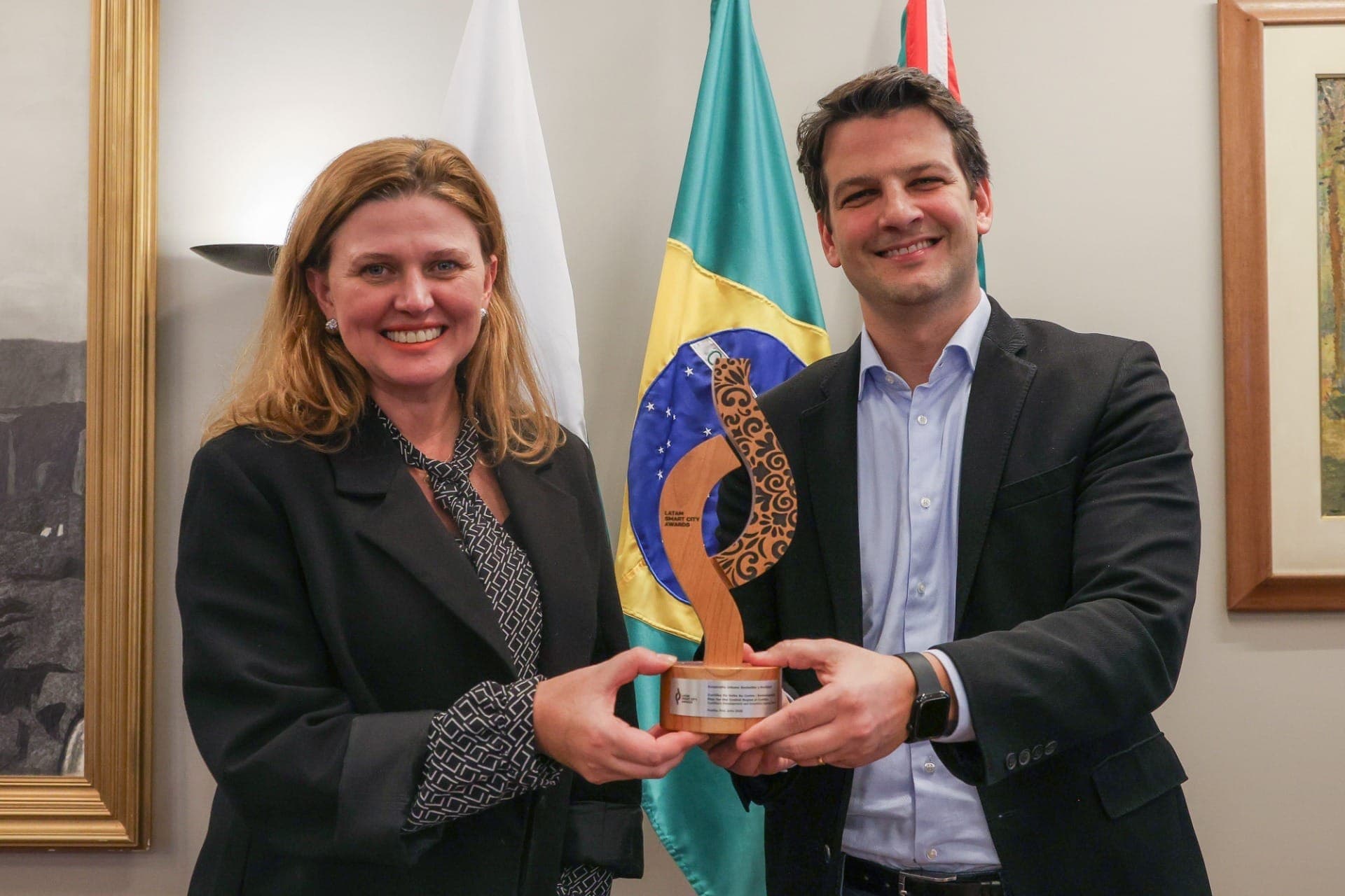 Prefeito Eduardo Pimentel recebe da assessora especial, Tatiana Turra, o troféu do Latam Smart City Awards 2026, conquistado pelo Curitiba de Volta ao Centro. Curitiba, 09/06/2026.