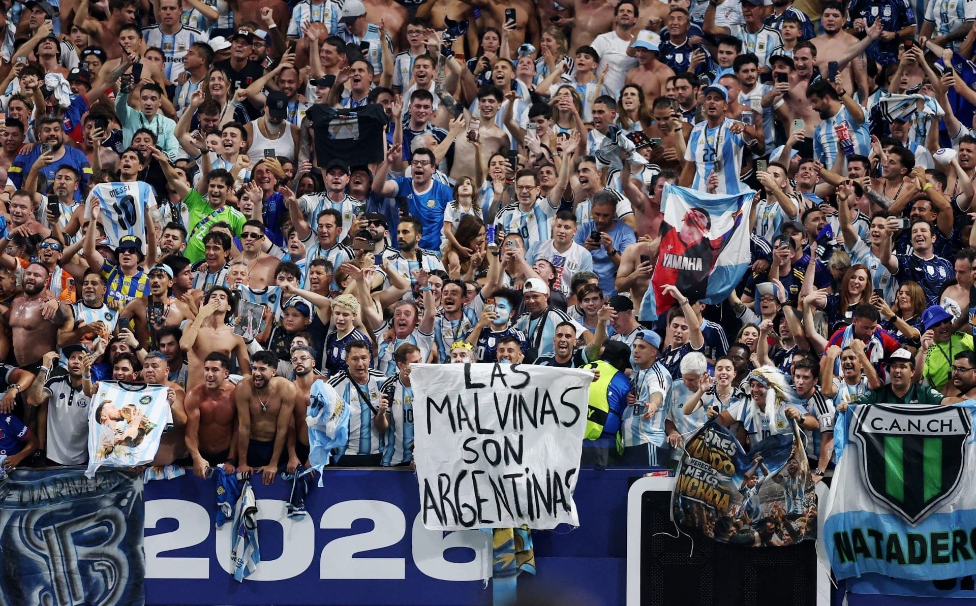 Torcedores da Argentina exibem faixa com mensagem sobre as Ilhas Malvinas enquanto comemoram após a partida.