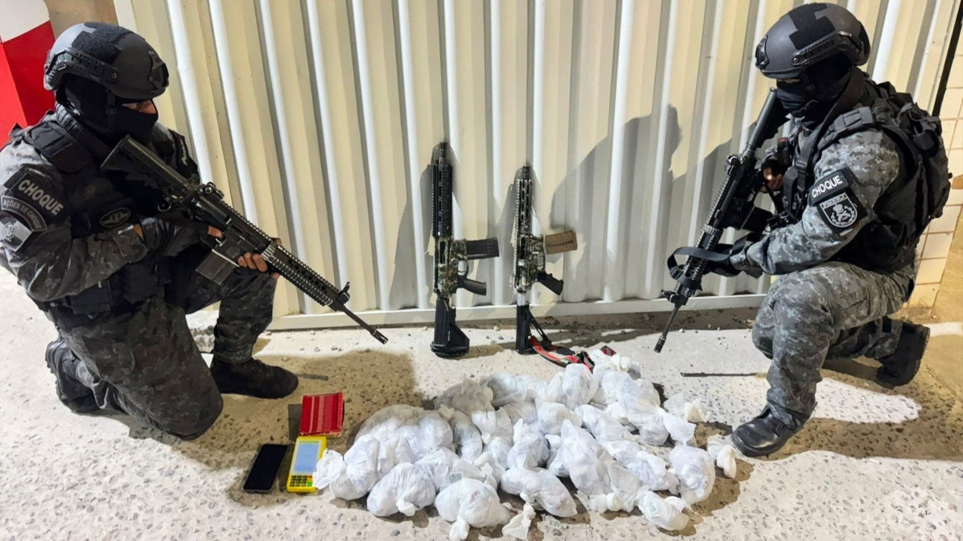 Policiais apreenderam drogas, dois fuzis, um celular e uma máquina de cartão.