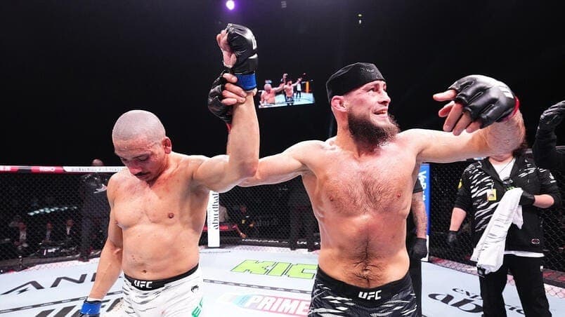 Rinat Fakhretdinov comemora a vitória no UFC 308 e levanta a mão de Carlos Leal.