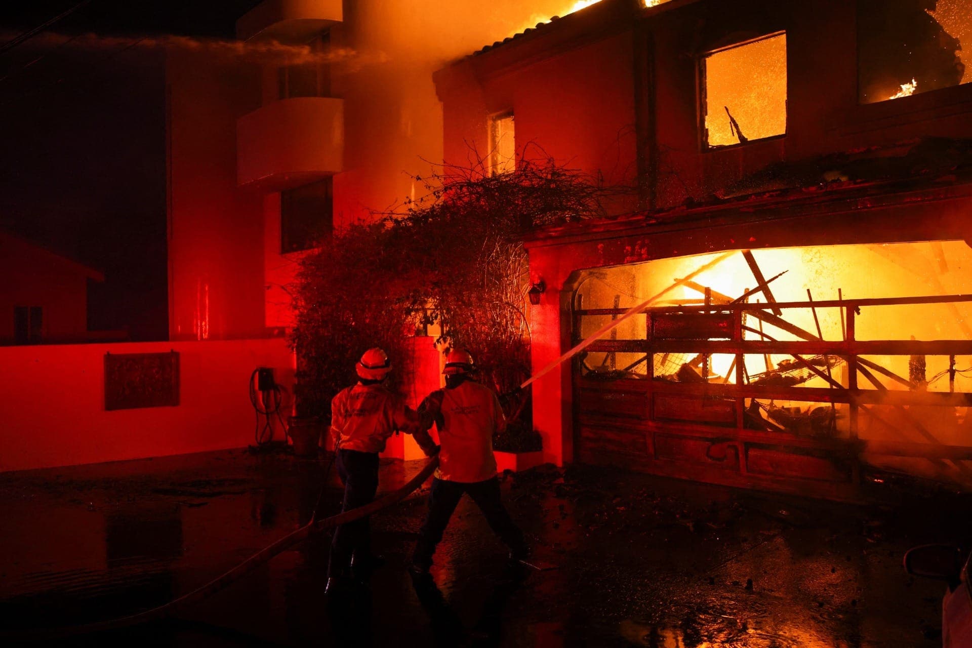Bombeiros combatem incêndio em uma casa em chamas, em Malibu, na Califórnia, em 8 de janeiro de 2025