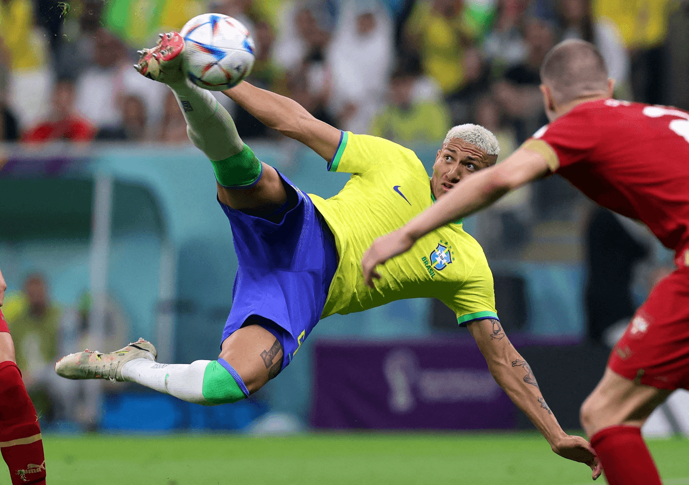 Richarlison gira o corpo e alcança a bola no ar com a perna